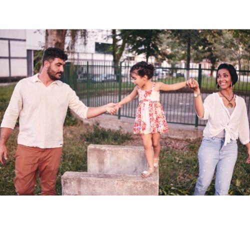 Parents holding hands of young child walking on wall