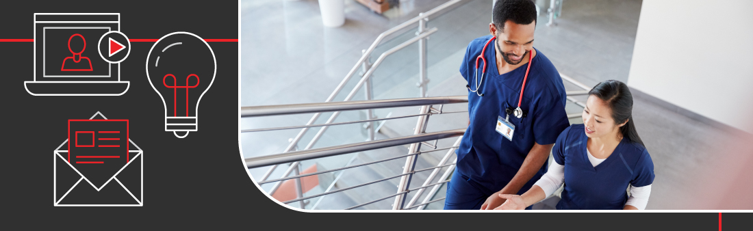 Two people in scrubs talking as they walk up the stairs