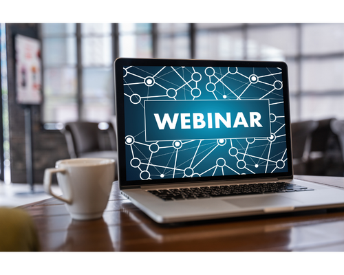 Laptop displaying the word "webinar" with coffee cup next to it